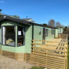 green caravan with large deking, sunny sky